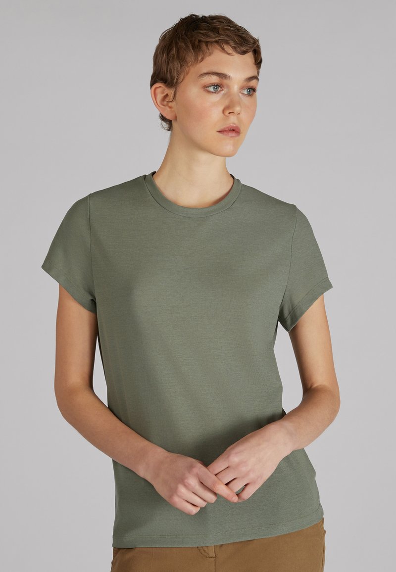 T-shirt z krótkim rękawem, okrągłym dekoltem w stonowanym oliwkowym kolorze. Wykonany z miękkiego, teksturowanego materiału, o luźnym kroju. Prosty design, bez wzorów.