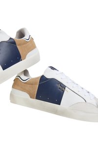 Las zapatillas presentan una combinación de cuero blanco, paneles de gamuza azul marino y topo. Cuerdas planas blancas y una suela de goma texturizada. Logo dorado en el lateral.