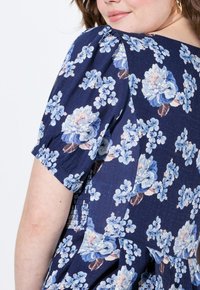 Květinové šaty s námořnickým pozadím, světlomodrými a růžovými květinami, krátkými nabíranými rukávy a zúžením v pase.