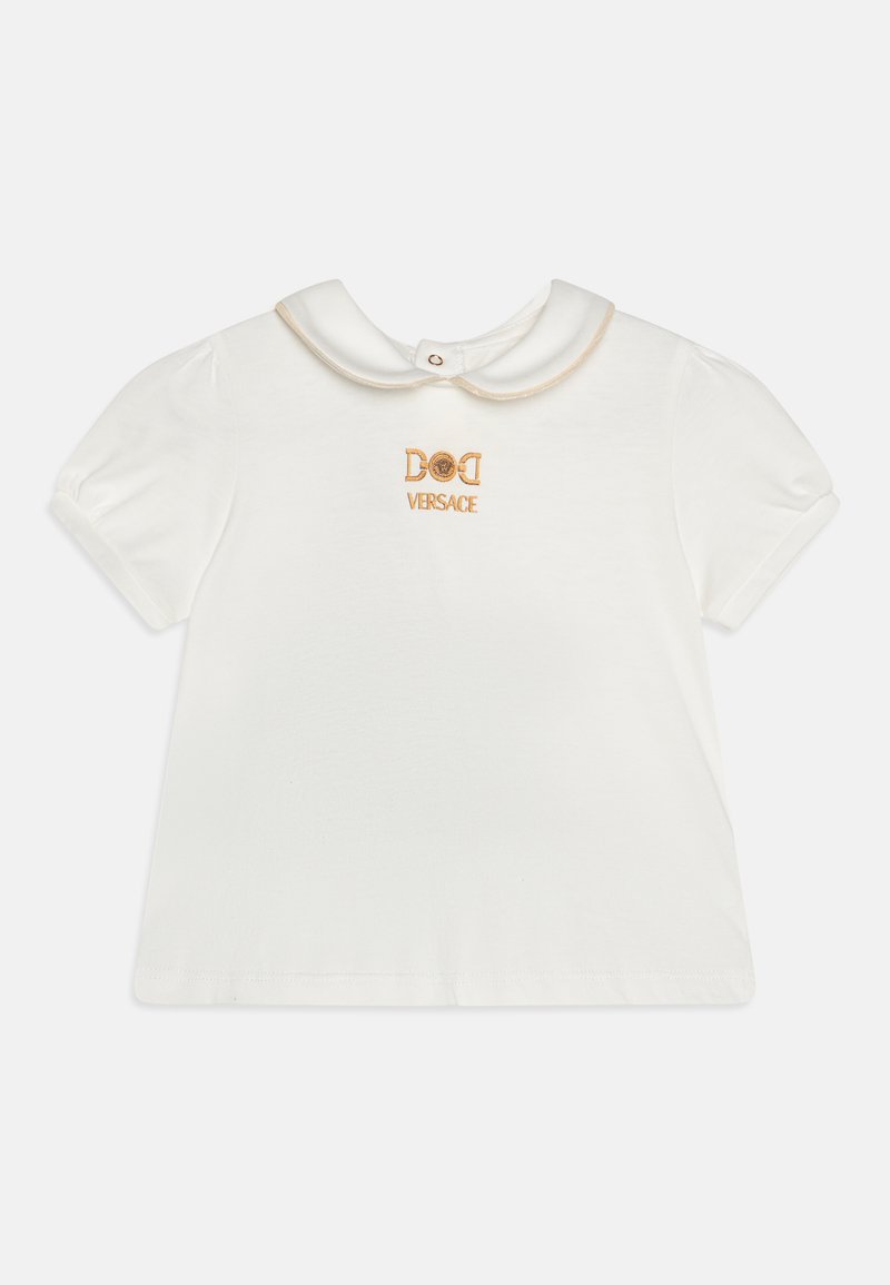 Balta trumpa rankovėmis marškinėliai su apvaliu apykakle, ant priekinės pusės išsiuvinėtas auksinis "DOLCE VERSACE" užrašas. Minkšta medvilninė medžiaga.