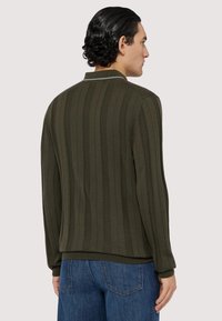 Olivově zelený svetr s vertikálně ribbovanou texturou, dlouhými rukávy a kulatým výstřihem. Má přiléhavý lem a manžety, vyrobený z měkké tkaniny.