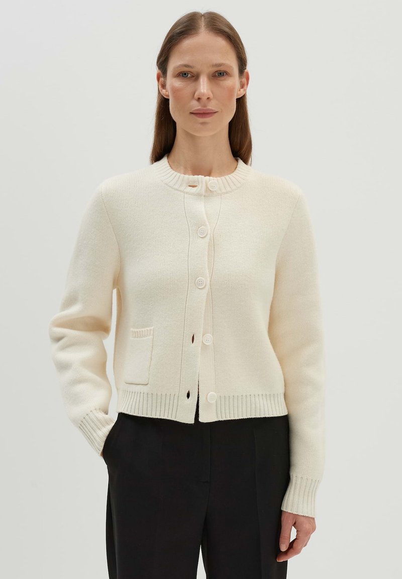 Cremefarbener Cardigan aus strukturiertem Strick, mit Rundhalsausschnitt, fünfknopfiger Verschluss und einer Fronttasche.