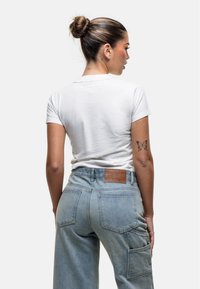 T-shirt bianco a maniche corte, in cotone, abbinato a pantaloni cargo in denim azzurro chiaro a vita alta con tasche a toppe e etichetta in pelle.