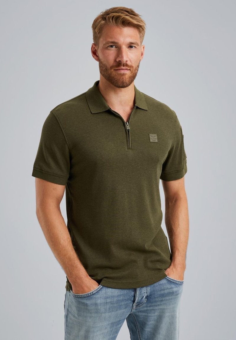 Polo shirt verde oliva con maniche corte, colletto con zip e dettaglio del logo sul petto, realizzato in un tessuto morbido e dalla texture piacevole.