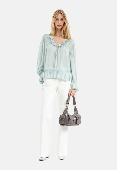 Blusa azzurra chiara con volant, scollatura a V e coulisse, abbinata a pantaloni bianchi a gamba larga e una borsa grigia strutturata con tasche.
