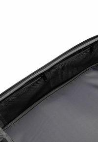 Interno di una borsa in tessuto grigio con una superficie liscia, dotato di due scomparti con cerniera e una tasca in rete per l'organizzazione.
