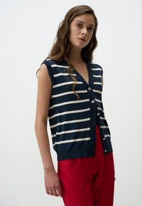 Marineblauwe en witte gestreepte mouwloze cardigan met een V-hals, voorzien van vijf zilveren knopen aan de voorkant en een geribbelde zoom.