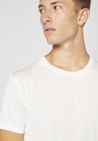 Vit bomull T-shirt med klassisk rund hals och korta ärmar, med en mjuk textur och en enkel design.