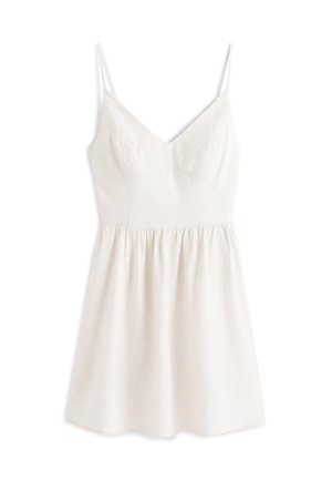 Robe blanche sans manches avec fines bretelles, corsage ajusté, fines rayures verticales et jupe froncée tombant au-dessus du genou.