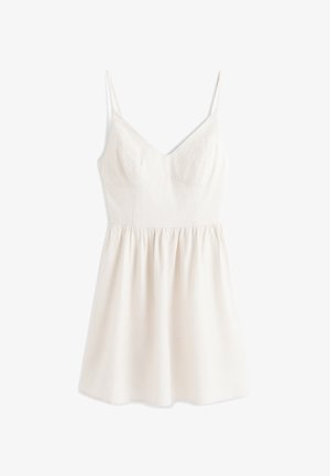 Robe blanche sans manches avec fines bretelles, corsage ajusté, fines rayures verticales et jupe froncée tombant au-dessus du genou.