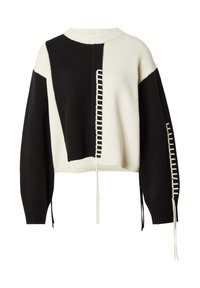 Pull en tricot court avec des panneaux géométriques noirs et crème, un col côtelé et des coutures décoratives le long des manches avec des liens suspendus.