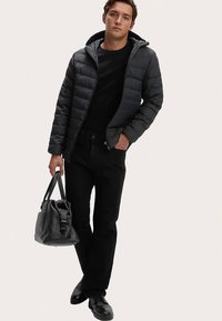 Sort dunjakke med hætte, båret over en sort skjorte. Sorte jeans og sko, holder en sort lædertaske. Enkelt design, tekstureret stof.