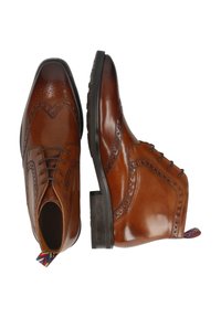Bottes brogue en cuir marron avec des perforations décoratives et des lacets, présentées de vues de dessus et de côté avec des tirettes colorées.
