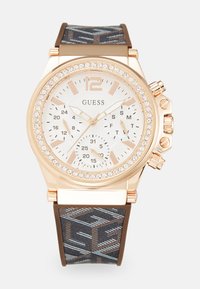 Złoty chronograf z błyszczącą obwódką, białą tarczą, brązowym silikonowym paskiem w wzory oraz wieloma sub-tarczami do śledzenia czasu.