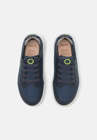 Zapatillas de malla azul marino con acentos en azul oscuro, ojales de cordón redondos y suela de goma texturizada. Diseño transpirable con logo visible.