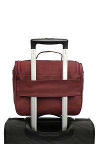 Dos maletas apiladas con un mango telescópico extendido; una bolsa más pequeña color burdeos asegurada en la parte superior de una bolsa negra más grande.