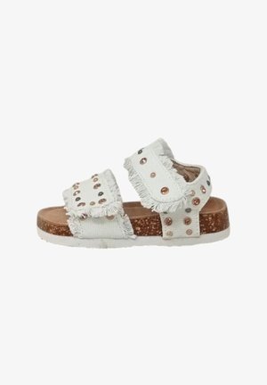 Sandali in tessuto bianco con bordi sfrangiati, decorati con borchie metalliche rotonde. Sottopiede in sughero e suola in gomma bianca. Cinghie regolabili per una vestibilità ottimale.