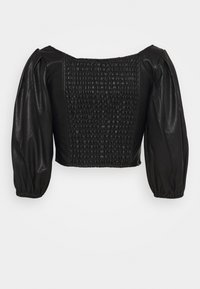 Schwarzes, bauchfreies Oberteil mit Puffärmeln, das einen strukturierten, gerafften Rückenteil und eine glatte Vorderseite aus Kunstleder aufweist. Gerüschte, elastische Bündchen.