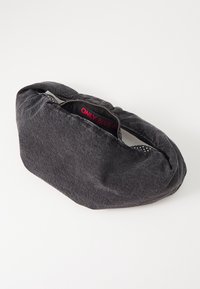 Svart denimväska med en mjuk, texturerad yta. Böjd form, dragkedjeöppning och en röd innertikett. Minimalistisk design, utan mönster.