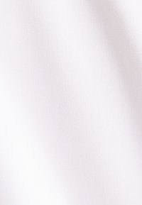 Gros plan d'un tissu blanc uni montrant une texture lisse et un motif de tissage subtil.