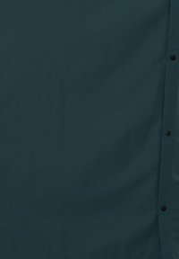 Dunkelgrüner Stoff mit glatter Textur, an einer Seite mit schwarzen Druckknöpfen versehen. Einfache, einfarbige Gestaltung ohne Muster oder Verzierungen.