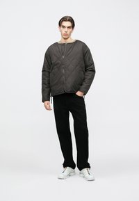 Tikk-kangaga tumehall jakk ümara kaelusega ja esiküljel lukk. Ühes mustade pükstega ja valgete tossudega, millel on mitmevärvilised aktsendid.