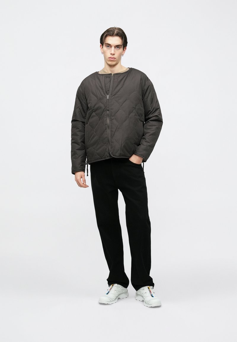 Tikk-kangaga tumehall jakk ümara kaelusega ja esiküljel lukk. Ühes mustade pükstega ja valgete tossudega, millel on mitmevärvilised aktsendid.