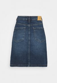 Jupe en denim de lavage foncé, avec une coupe droite, deux poches arrière et une étiquette en cuir signée à la taille. Ourlet propre sans embellissements.