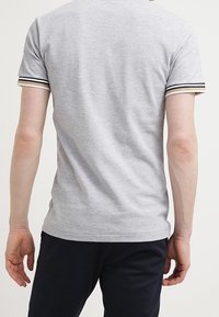 Szara bawełniana koszulka z krótkimi rękawami, z czarno-białymi paskami na mankietach, o gładkiej fakturze i dopasowanym kroju.