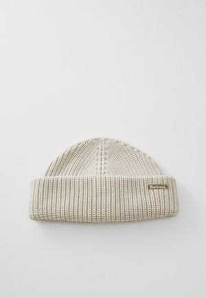 Beige knitted hat with a cuffed design, featuring ribbed texture and a small gold logo tag on the side.