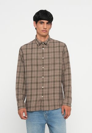 Brown plaid long-sleeve shirt with a button-down collar, featuring white buttons and a slightly textured fabric. Worn with light blue jeans.