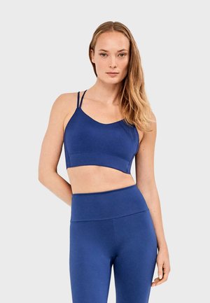 Sujetador deportivo de tela azul intenso con tirantes finos y ajustables, con escote redondo y textura lisa y sin costuras. Leggings a juego de talle alto.