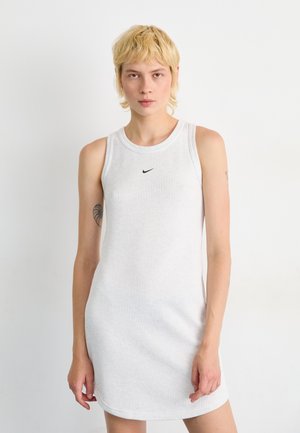 White ribbed tank dress with a round neckline and sleeveless design, featuring a small black Nike logo on the chest. Smooth texture.