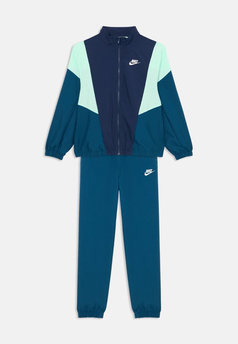 Dvoudílný sportovní overal Nike v námořnické modré, tyrkysové a světle mátové zelené barvě, se zipovou bundou a elastickými manžetami, s bílými logy Nike.