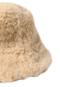 Beige bucket hat lavet af blød, krøllet stof. Har en rund krone og en blød skygge med en struktureret, fuzzy overflade.