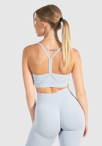Sostenedor atlético de color azul claro con diseño de espalda nadadora, textura sin costuras y tela acanalada, combinado con leggings de talle alto a juego.