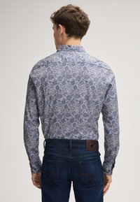 Blauwe bloempatronen lange mouwen shirt met een gespreide kraag, knoopmanchetten en een rechte zoom, gecombineerd met donkere denim jeans.