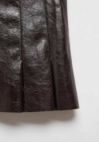 Gonna in pelle marrone con una finitura lucida, caratterizzata da pieghe verticali per texture e movimento, esposta su uno sfondo neutro.