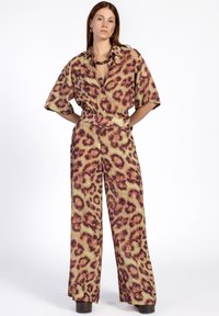 Twee-delig outfit bestaande uit een kortärmige button-up shirt en wijde broek in een groen en bruin luipaardprint.