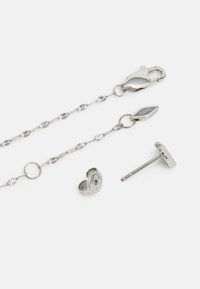 Ensemble de bijoux en métal argenté comprenant une chaîne ornée d'accents floraux, un fermoir en mousqueton et des boucles d'oreilles à clous rondes avec un fini poli.