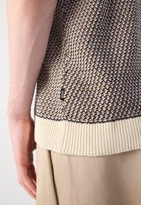 Maglione lavorato a maglia con motivo a fantasia in tonalità marrone e crema, orlo a coste crema, etichetta laterale con la scritta "BOSS". Texture ben evidenziata.