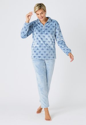Ensemble de vêtements d'intérieur en polaire bleu clair avec des motifs de cœurs bleu foncé. Le haut est doté d'un col zippé ; le bas est doux et confortable.