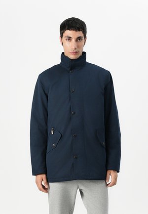 Navy blue coat with high collar, front buttons, dual side pockets, and a textured fabric. Features minimal design and practical detailing.