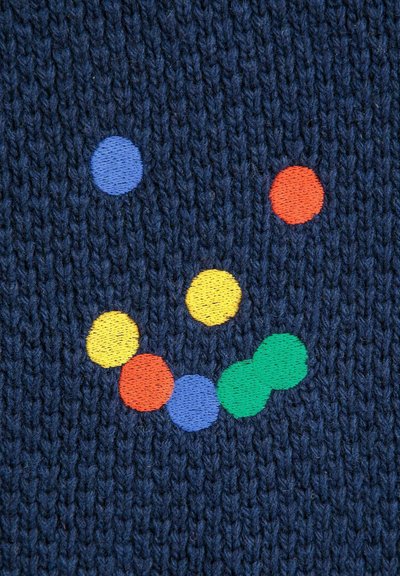 Pleteni materijal u tamnoplavoj boji sa izvezenim šarenim točkicama: narančastom, žutom, plavom, zelenom i crvenom, raspoređenim u uzorak nasmijanih lica.