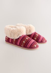 Chaussons en tricot avec un extérieur à motifs roses et rouges, dotés d'un bord en fausse fourrure douce et d'une semelle en caoutchouc beige pour la durabilité.