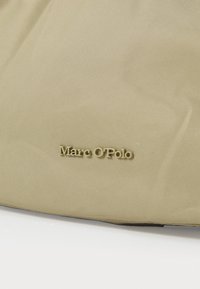 Borsa di tessuto beige con una superficie liscia, caratterizzata da un logo in oro goffrato "Marc O'Polo" sul davanti. Forma rettangolare semplice.