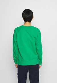 Sweatshirt en coton vert avec des manches raglan, col et poignets côtelés. Présente un tissu texturé et un design simple. Vue de dos montrée.