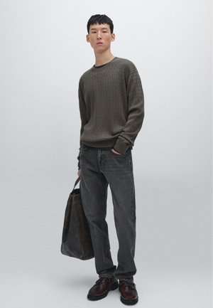 Olivgrön ribbad stickad tröja, mörkgrå jeans, bruna läderskor och en brun totebag. Enkla, texturerade material med en avslappnad passform.