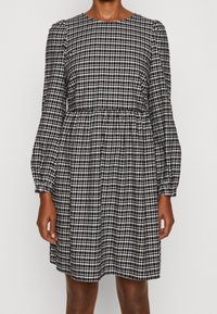 Svart och vit rutigt klänning med långa puffärmar, rundad halsringning och elastisk midja, med en flödande kjol.