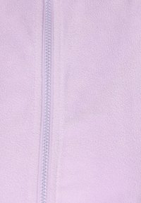 Tessuto in pile di un delicato viola chiaro con una superficie liscia presenta una cerniera centrale. La cerniera ha un design con piccole dentature rotonde e nastro di colore abbinato.